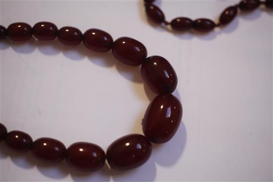 Two single strand red simulated amber bead necklaces, largest 158cm.